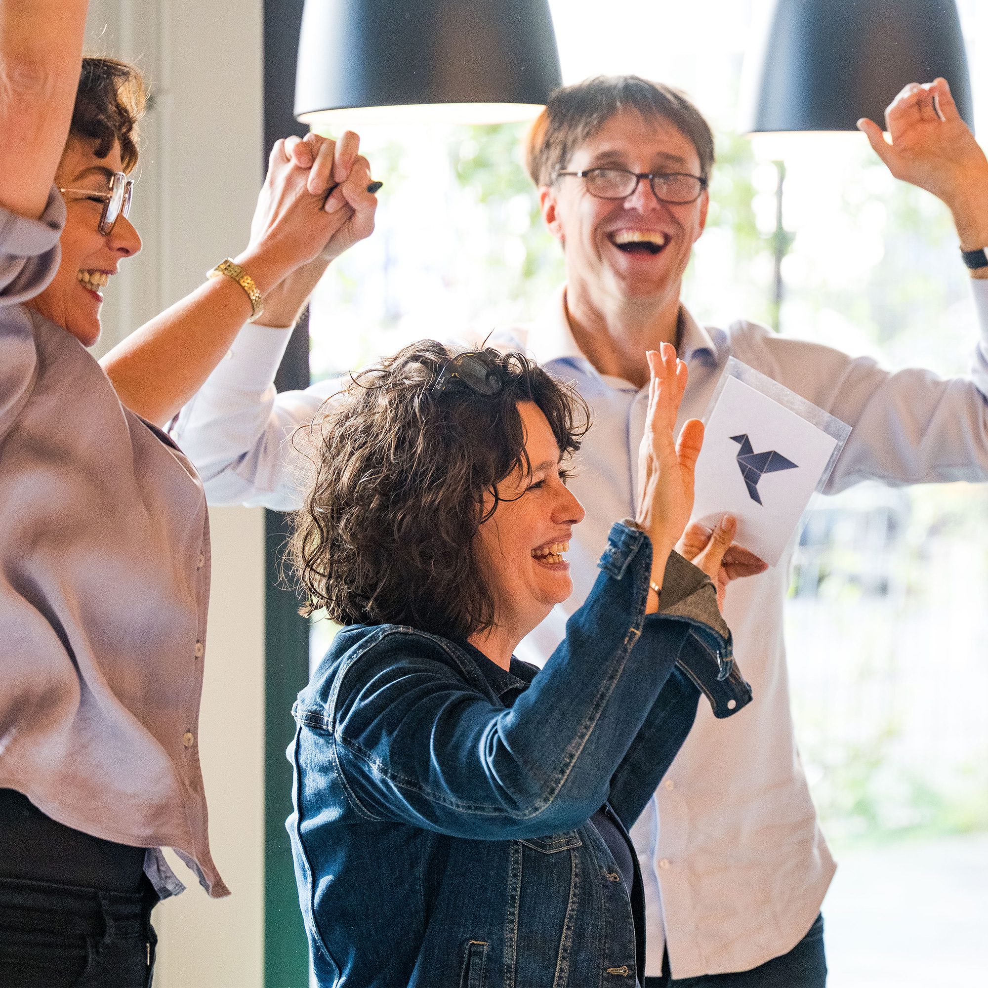 Trainer faciliteert een actieve werkvorm: 3 deelnemers in een trainingsruimte.