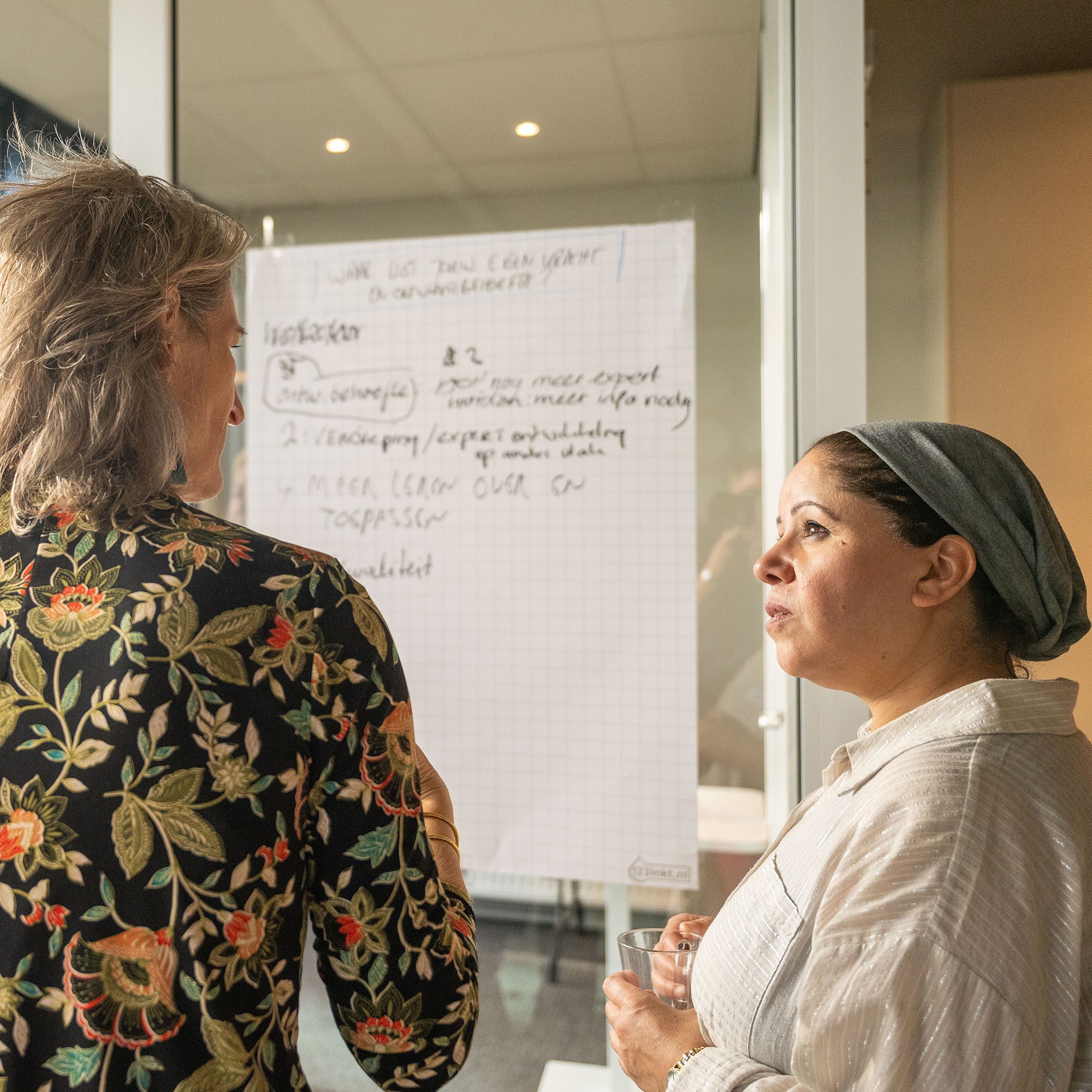 Leidinggevende in gesprek met medewerker tijdens een leertraject over teamontwikkeling en gedragsverandering op de werkvloer.